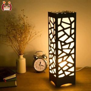 Light Weight Table Lamp This beautifully designed wooden lamp features intricate laser cutting on a 2.8mm MDF wooden sheet, providing a relaxing ambiance when illuminated. The lamp stands at 15.5 inches high and 4.5 inches wide, making it a perfect addition to any room. It utilizes LED SMD technology with a warm white or golden light, creating stunning patterns on the walls at night. Lightweight and portable