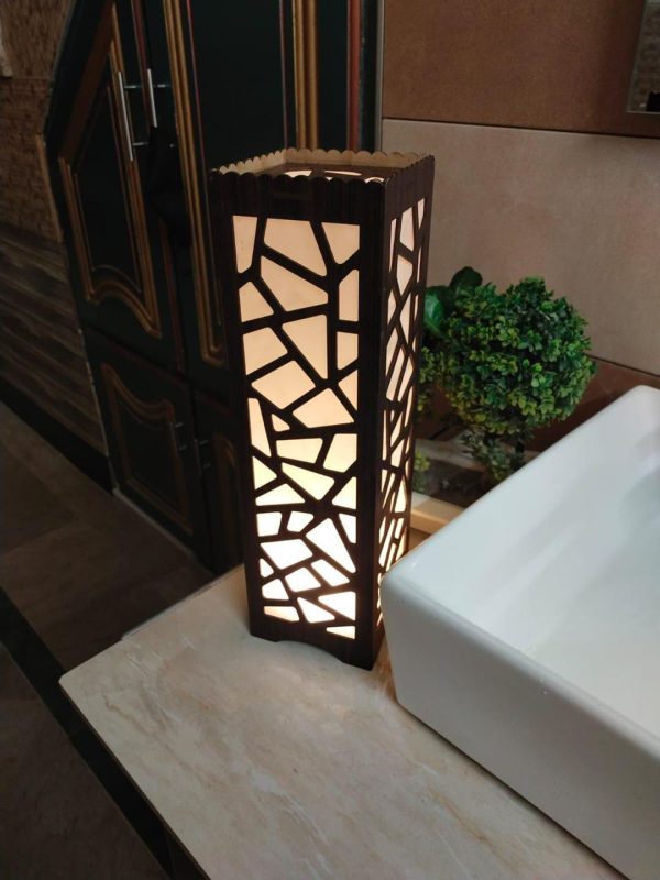 Light Weight Table Lamp This beautifully designed wooden lamp features intricate laser cutting on a 2.8mm MDF wooden sheet, providing a relaxing ambiance when illuminated. The lamp stands at 15.5 inches high and 4.5 inches wide, making it a perfect addition to any room. It utilizes LED SMD technology with a warm white or golden light, creating stunning patterns on the walls at night. Lightweight and portable