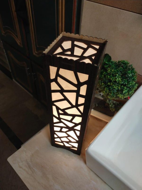 Light Weight Table Lamp This beautifully designed wooden lamp features intricate laser cutting on a 2.8mm MDF wooden sheet, providing a relaxing ambiance when illuminated. The lamp stands at 15.5 inches high and 4.5 inches wide, making it a perfect addition to any room. It utilizes LED SMD technology with a warm white or golden light, creating stunning patterns on the walls at night. Lightweight and portable